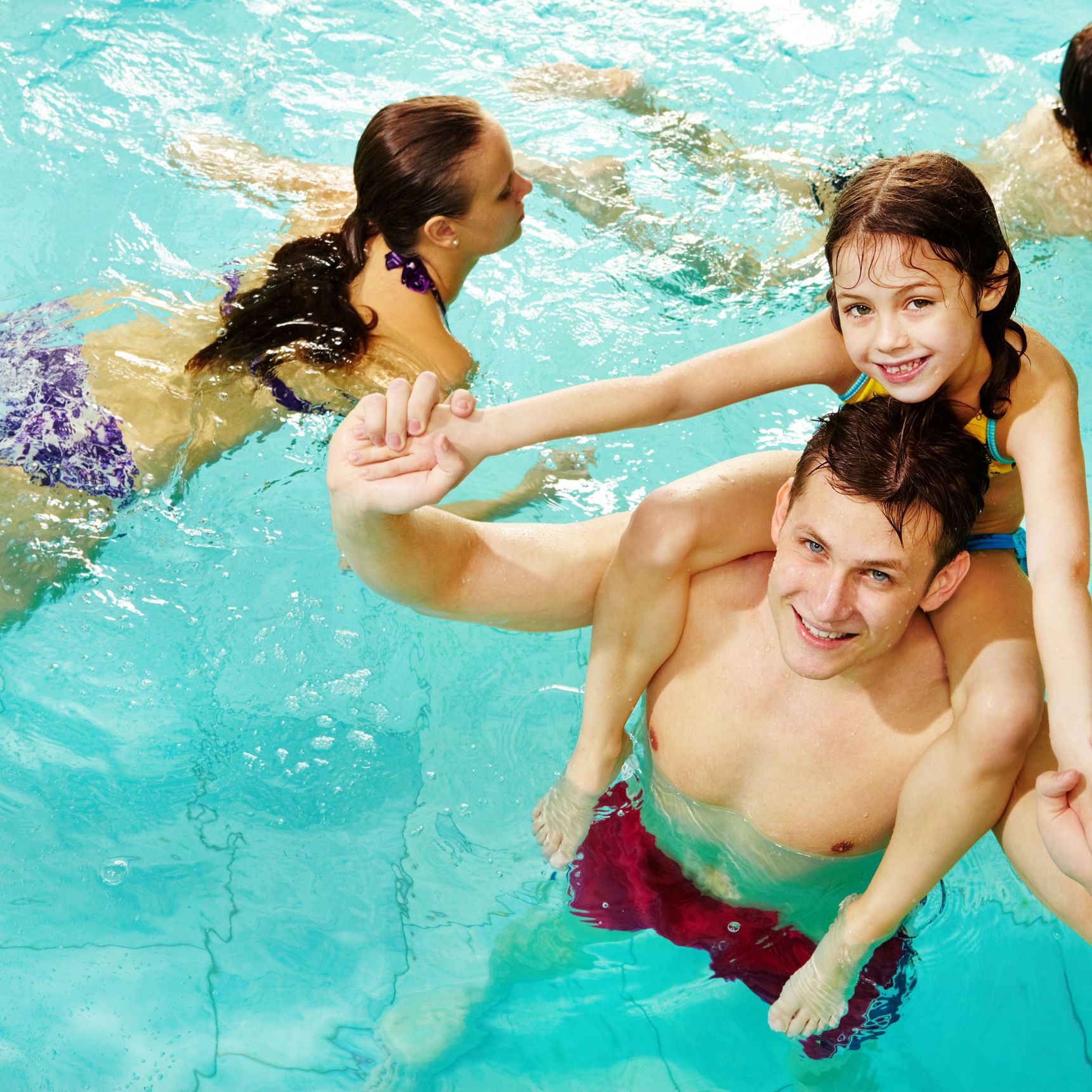 Ung mand med pige på skulderen i vandet